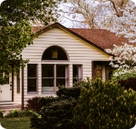 The exterior of a beige suburban home with a landscaped yard. 